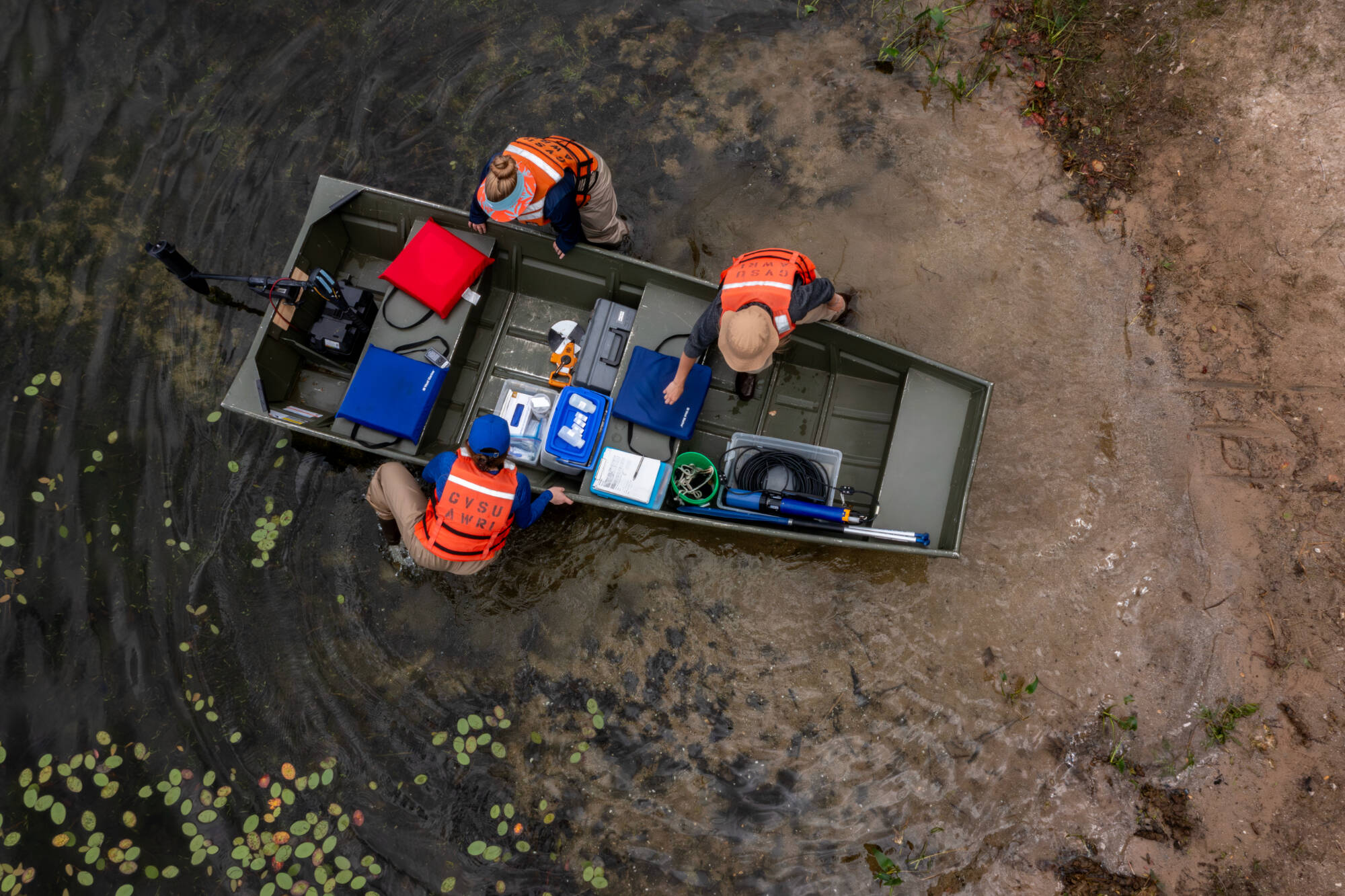 Overhead shot of three technicians launching a small boat.